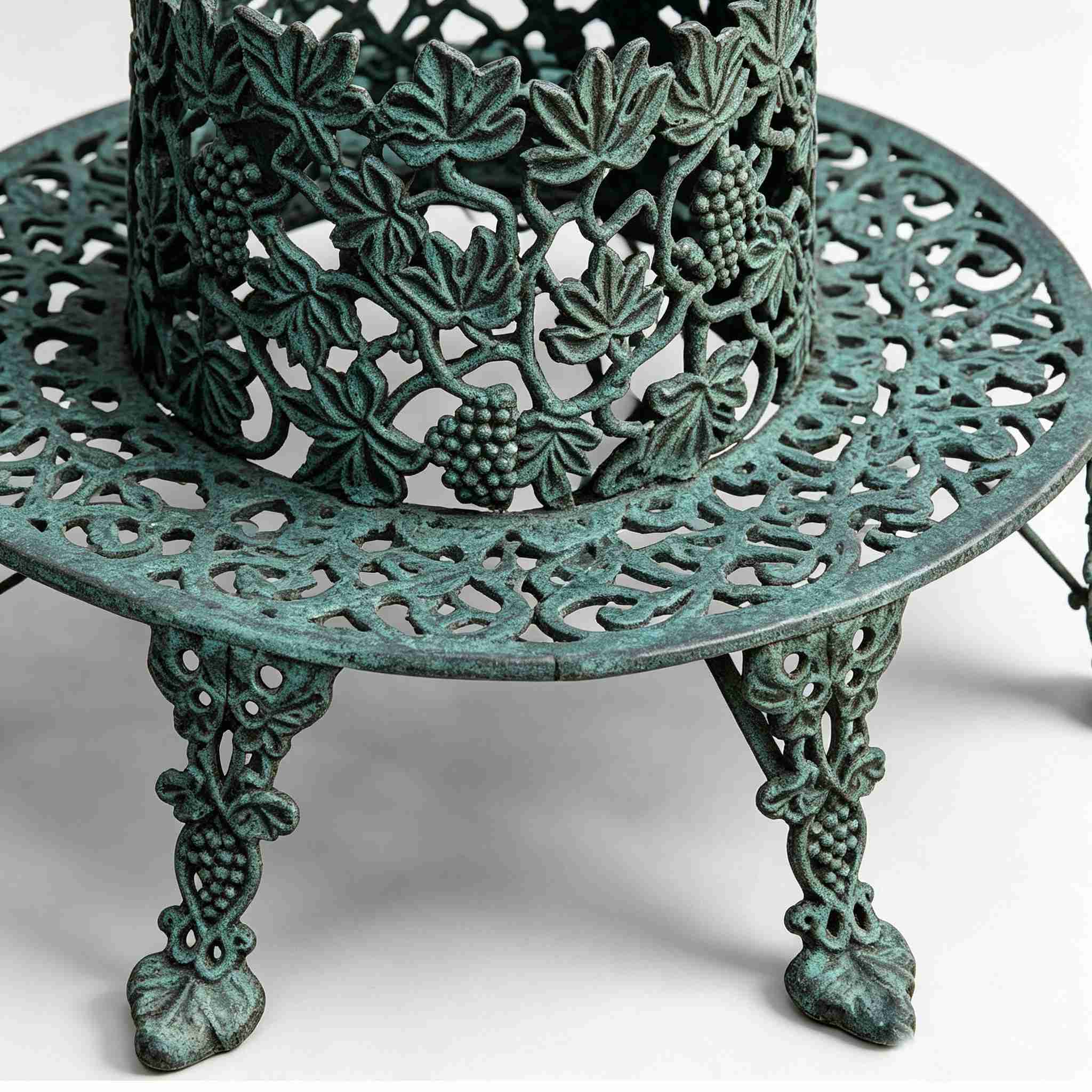 Close up detail shot of verdigris cast iron tree bench, intricate openwork grape vine, grape cluster and leaf relief carving, decorative grape patterned legs
